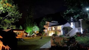 Una casa moderna de dos pisos con un patio delantero bien iluminado y una escalera que lleva a la entrada.