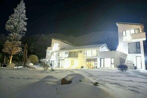 A modern two-story house with a snow-covered driveway and a mountain backdrop. - Yueguo Shanqiu Hostel (Hangzhou)