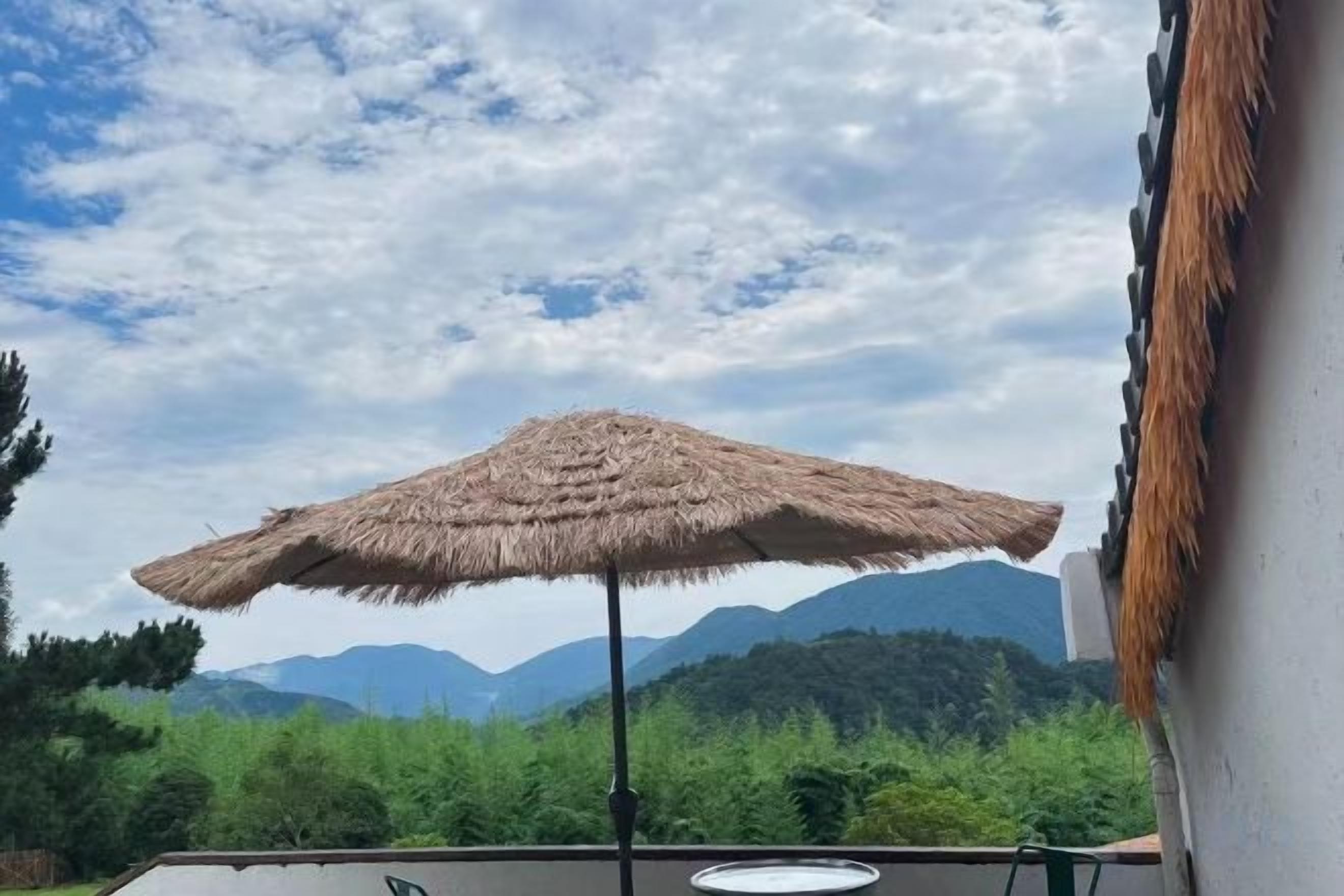 A thatched umbrella on a balcony with a mountain view in the background.