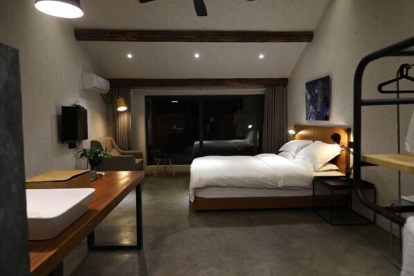 Une chambre d’hôtel moderne équipée d’un lit, d’une table de chevet et d’un bureau avec une chaise.