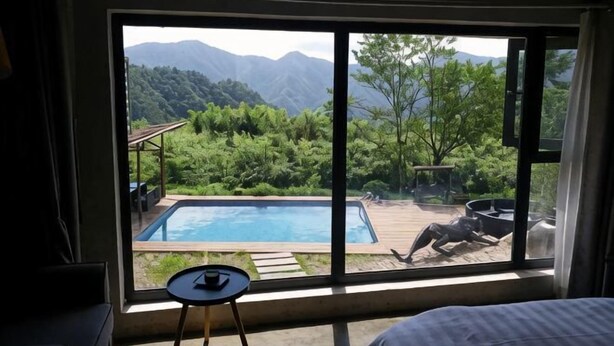 Una habitación con un ventanal grande con vistas a una piscina y montañas.