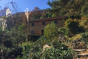 Un bâtiment en pierre doté d’un toit plat, entouré d’une végétation luxuriante et surplombant un ciel dégagé.