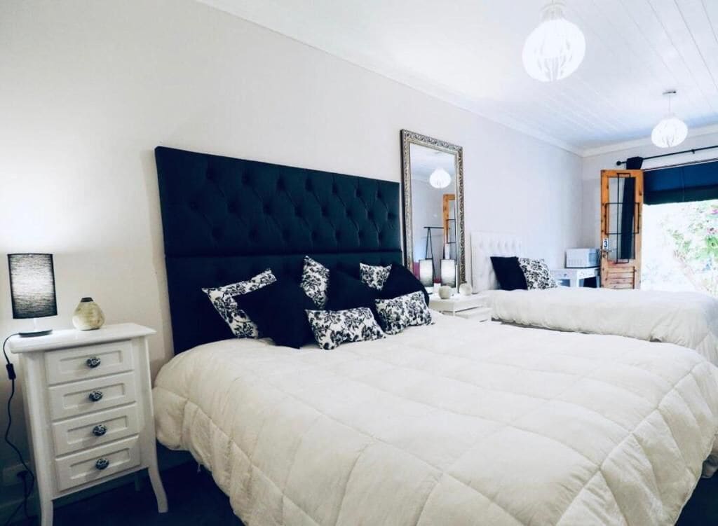 A bedroom with two beds, a nightstand, a mirror, and a dresser.