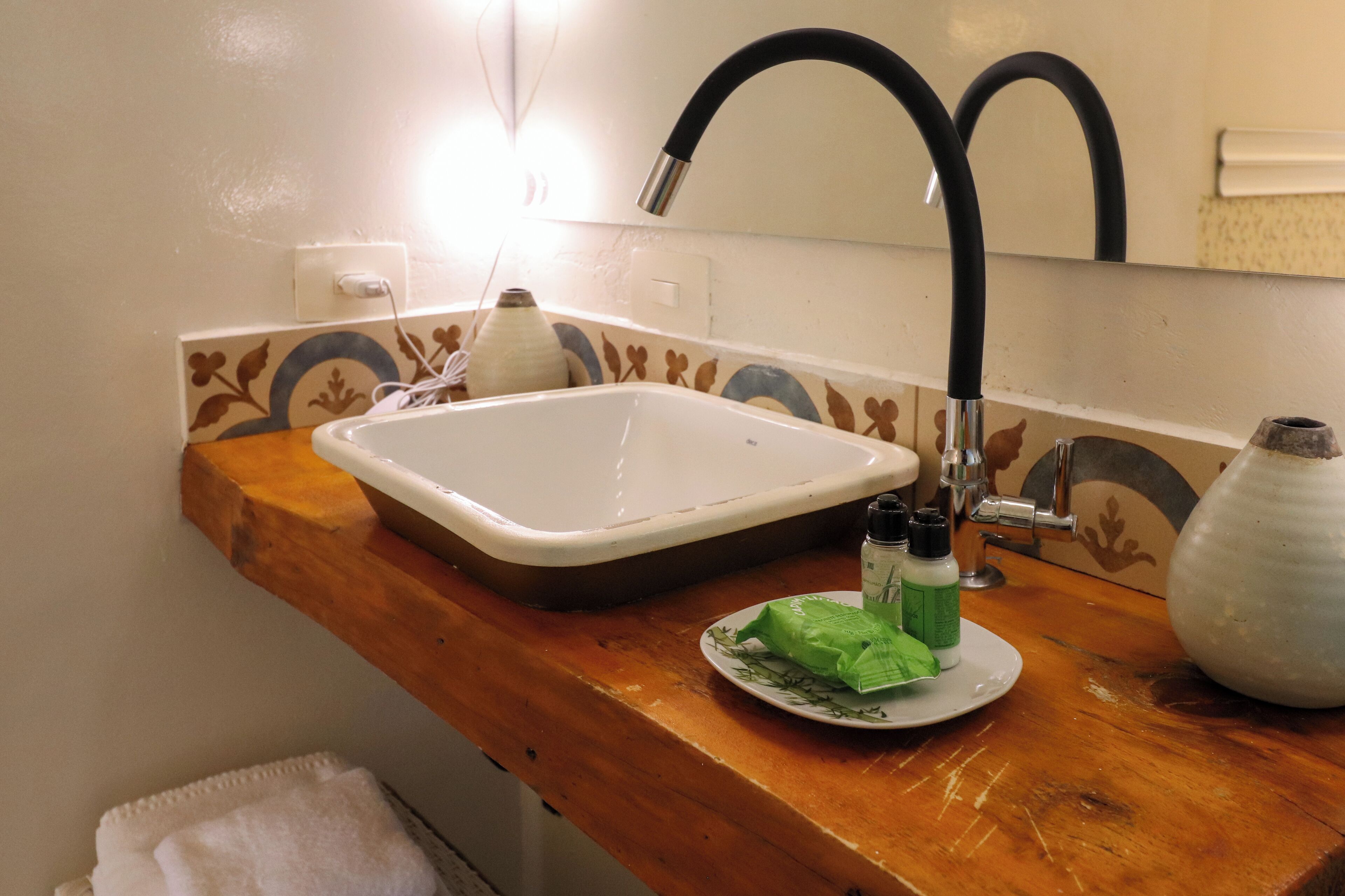 Un baño con tocador de madera, un lavamanos blanco y un espejo.