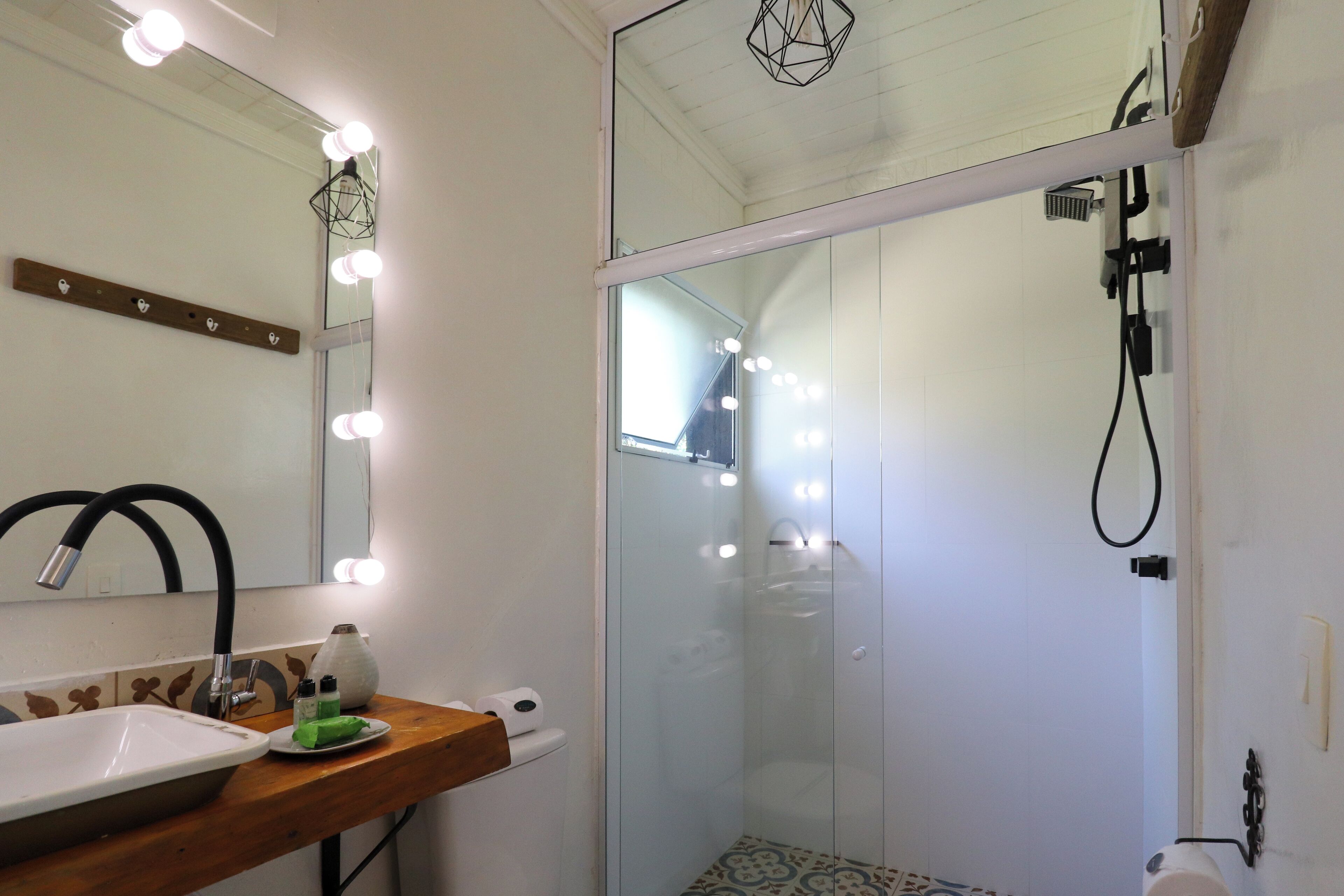 A bathroom with a vanity, mirror, lights, and a shower enclosure.