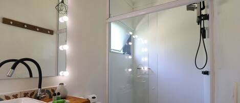 A bathroom with a vanity, mirror, lights, and a shower enclosure.
