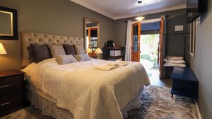A large bed with a tufted headboard, a bedside table with a lamp, and a mirror on the wall.