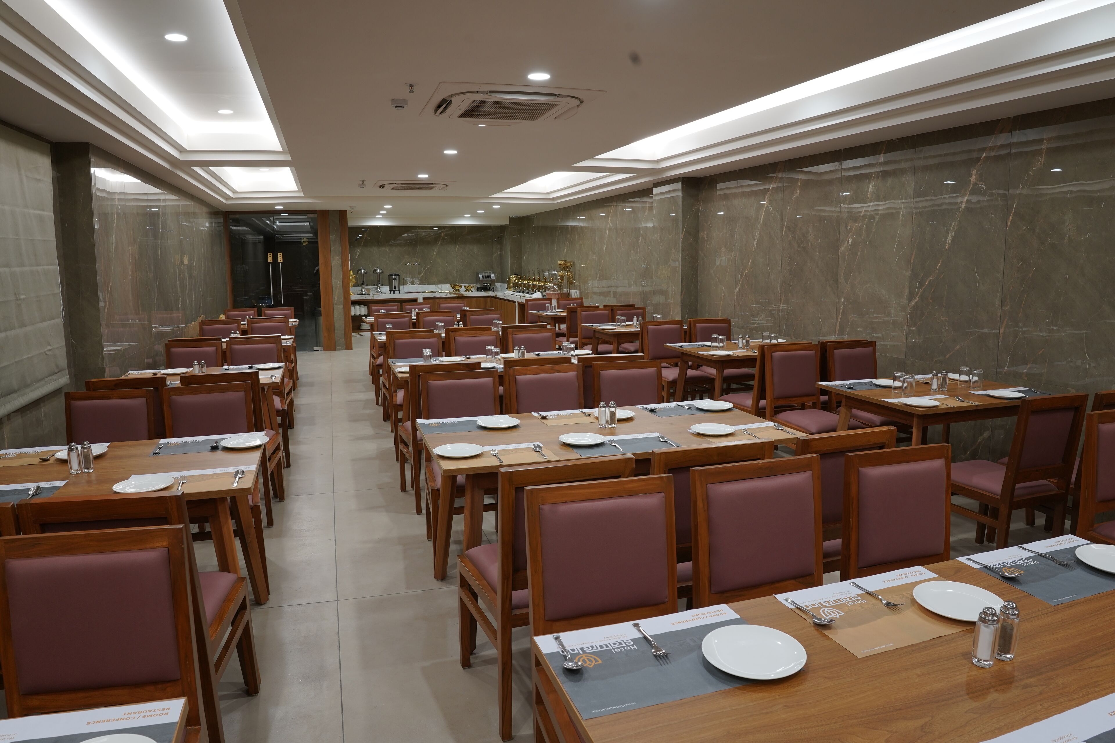 Un'ampia sala da pranzo con diversi tavoli e sedie, disposti in file.