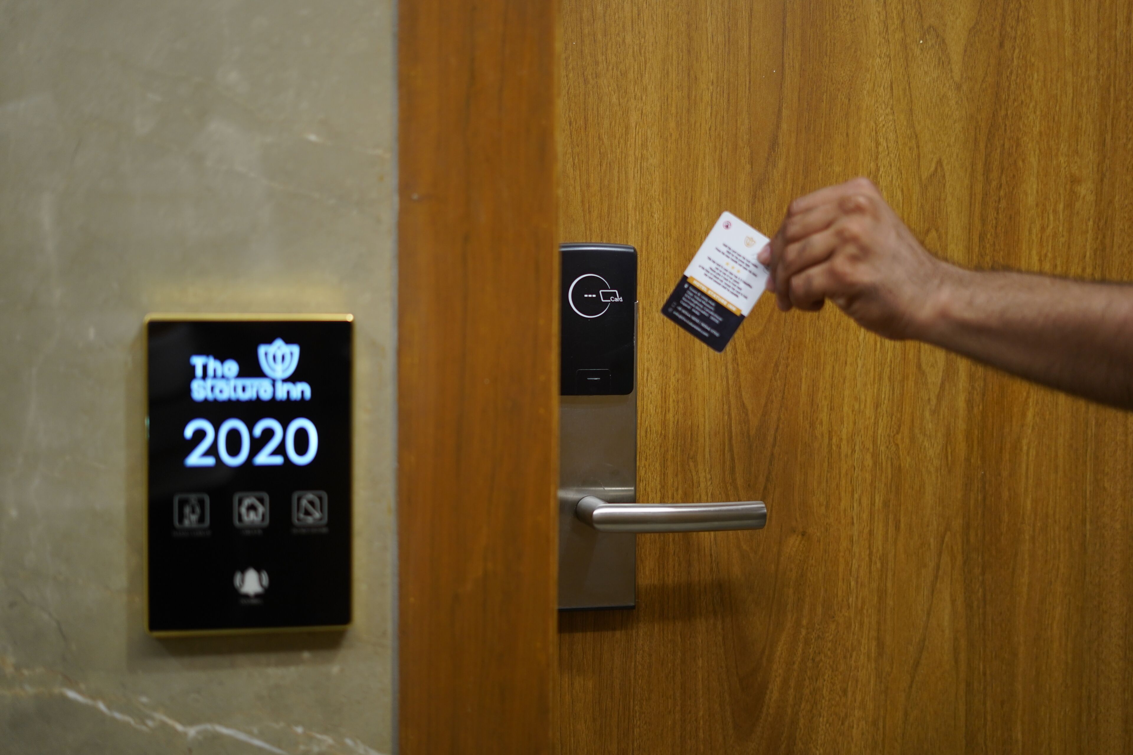Een digitale kaartlezer met de naam van het hotel en het jaartal, een metalen deurklink en een houten deur.