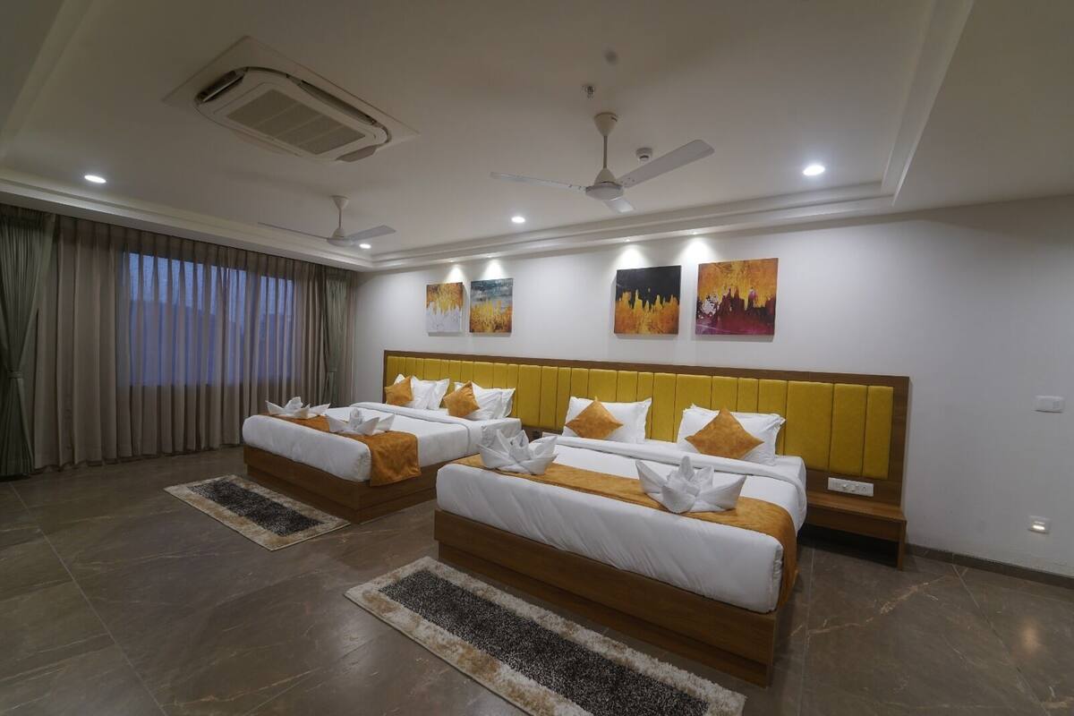 A hotel room with two beds, a ceiling fan, recessed lighting, and artwork on the walls.