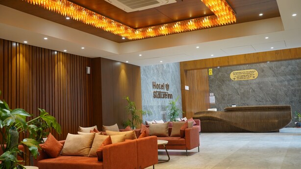 En hotellobby med en receptionsdisk, soffor och krukväxter.