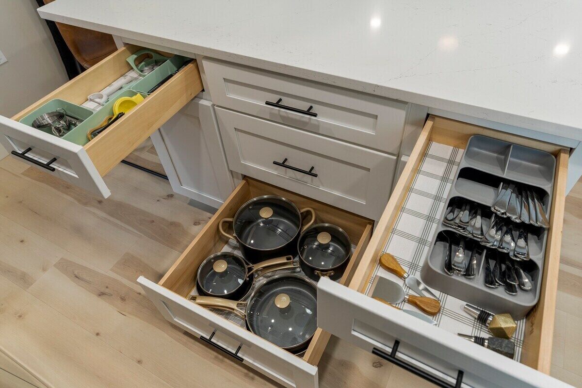 A kitchen with multiple drawers, including a utensil organizer and a pot rack.