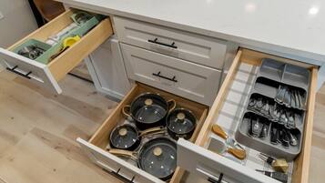A kitchen with multiple drawers, including a utensil organizer and a pot rack.
