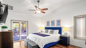 Una camera da letto con un letto, un ventilatore a soffitto, un comodino, una panca e vista sull'esterno.