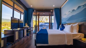 A modern hotel room with a large bed, a desk with a flat-screen TV, and a balcony with a scenic view. - Tea Resort Prenn (Xuan Huong - Da Lat)