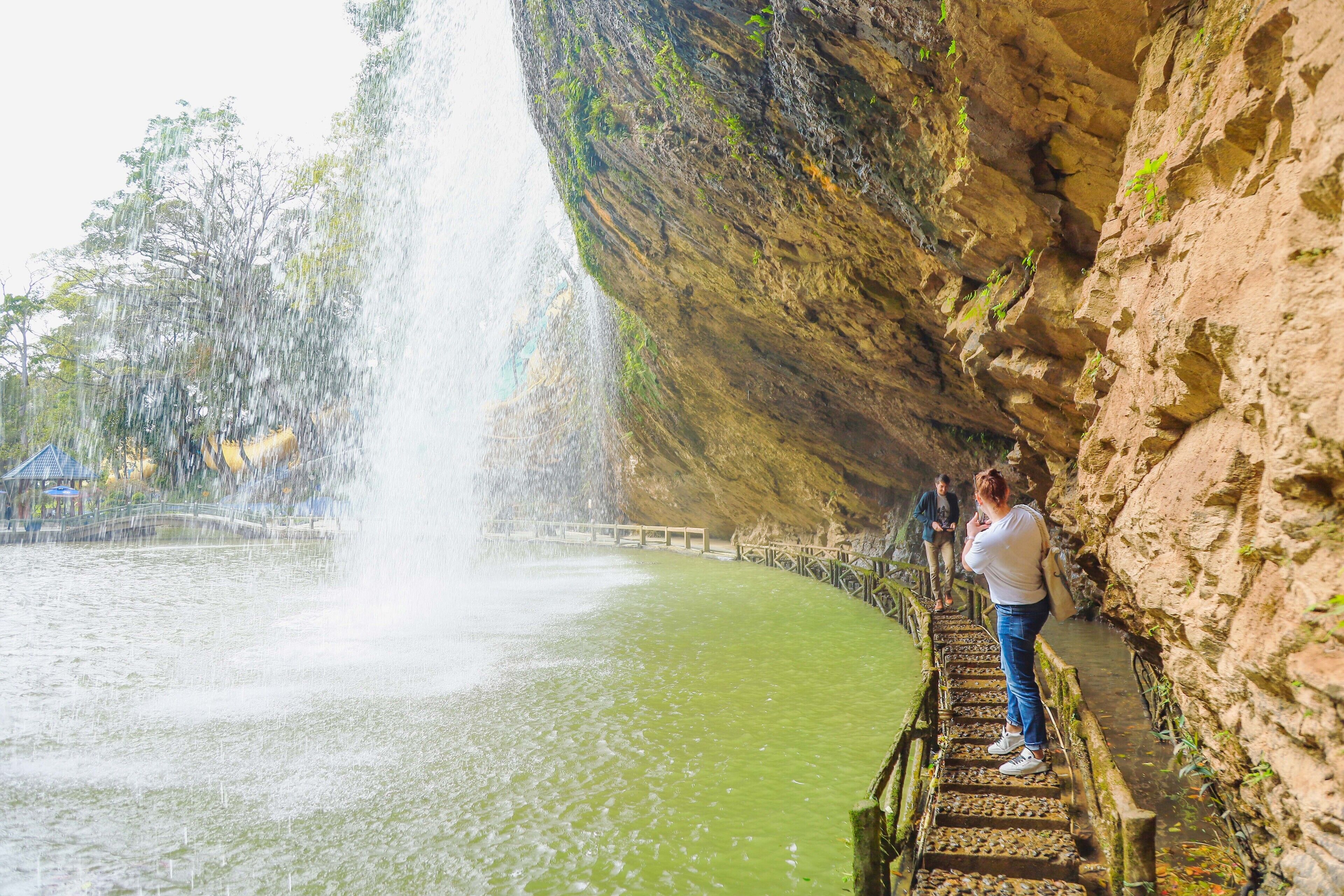 A person standing on a stone staircase next to a waterfall.