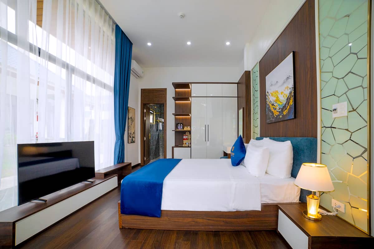 Une chambre d’hôtel moderne, dotée d’un grand lit, d’une télévision et d’une lampe de chevet.