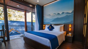 A hotel room with a large bed, a view of mountains through a glass door, and a balcony with a view of the mountains. - Tea Resort Prenn (Xuan Huong - Da Lat)
