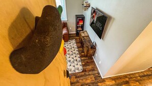 Una habitación con piso de madera, un sofá, una mesa de centro y un televisor montado en la pared.