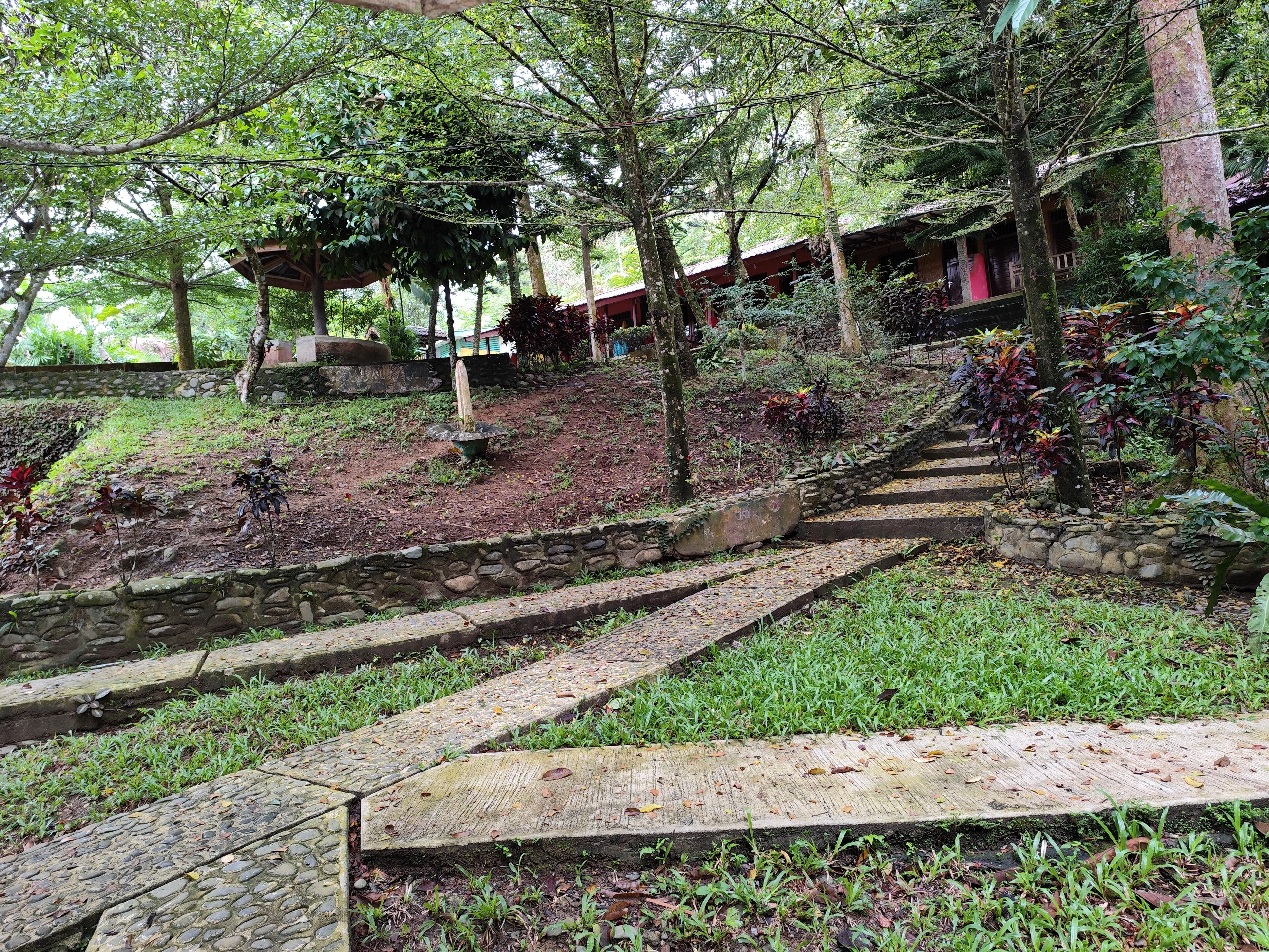 Una escalera de piedra que sube una colina, con una terraza de madera en la cima.