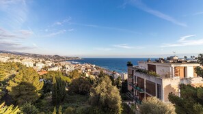 Paisagem costeira com vista para o mar, edifícios e vegetação.