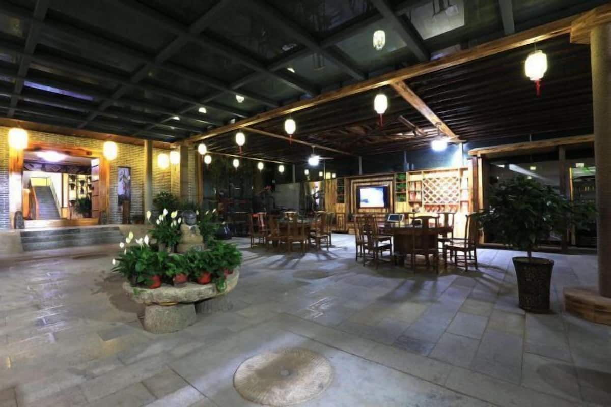 An indoor area with stone flooring, wooden tables and chairs, and hanging spherical lights.