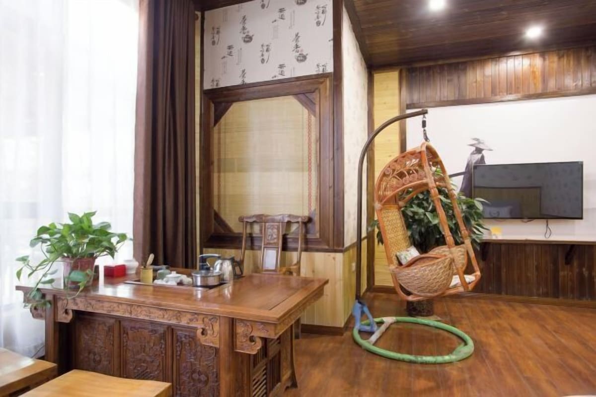 A wooden dining table with a hanging chair, a potted plant, and a television on a stand.