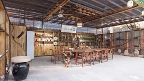 A rustic wooden interior with a central dining table and chairs, surrounded by shelves with various items. - Mount Hua Hongchen Xiake Themed Homestay (Huayin)