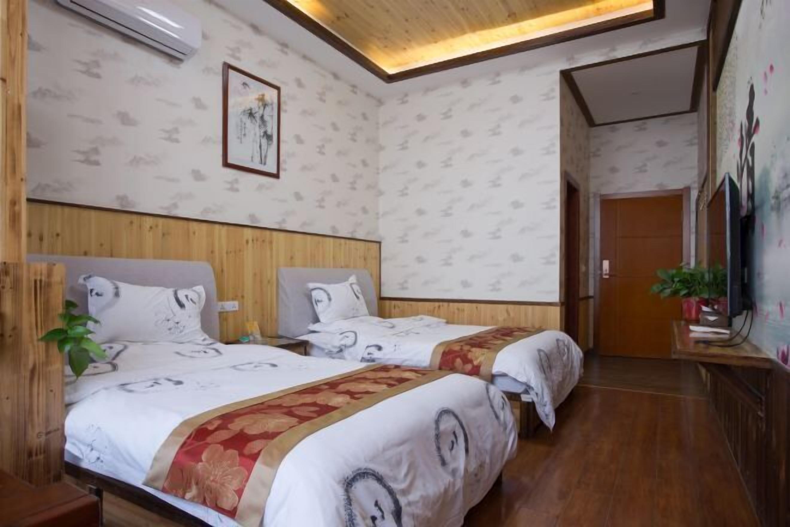 A hotel room with two beds, wooden paneling, a ceiling light, and a painting on the wall.