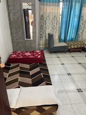 A room with a sofa bed, a chair, a small table, and a wardrobe. - Tripti The Boutique Hotel (Rishikesh)