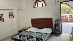 A bedroom with a bed, a headboard, a window, and a door leading to an outdoor area. - Tripti The Boutique Hotel (Rishikesh)