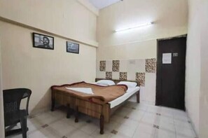 A single bed with a wooden frame and a brown bedspread in a room with tiled flooring and a black door. - Tripti The Boutique Hotel (Rishikesh)