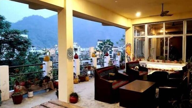 A covered outdoor seating area with a view of the city and mountains. - Tripti The Boutique Hotel (Rishikesh)