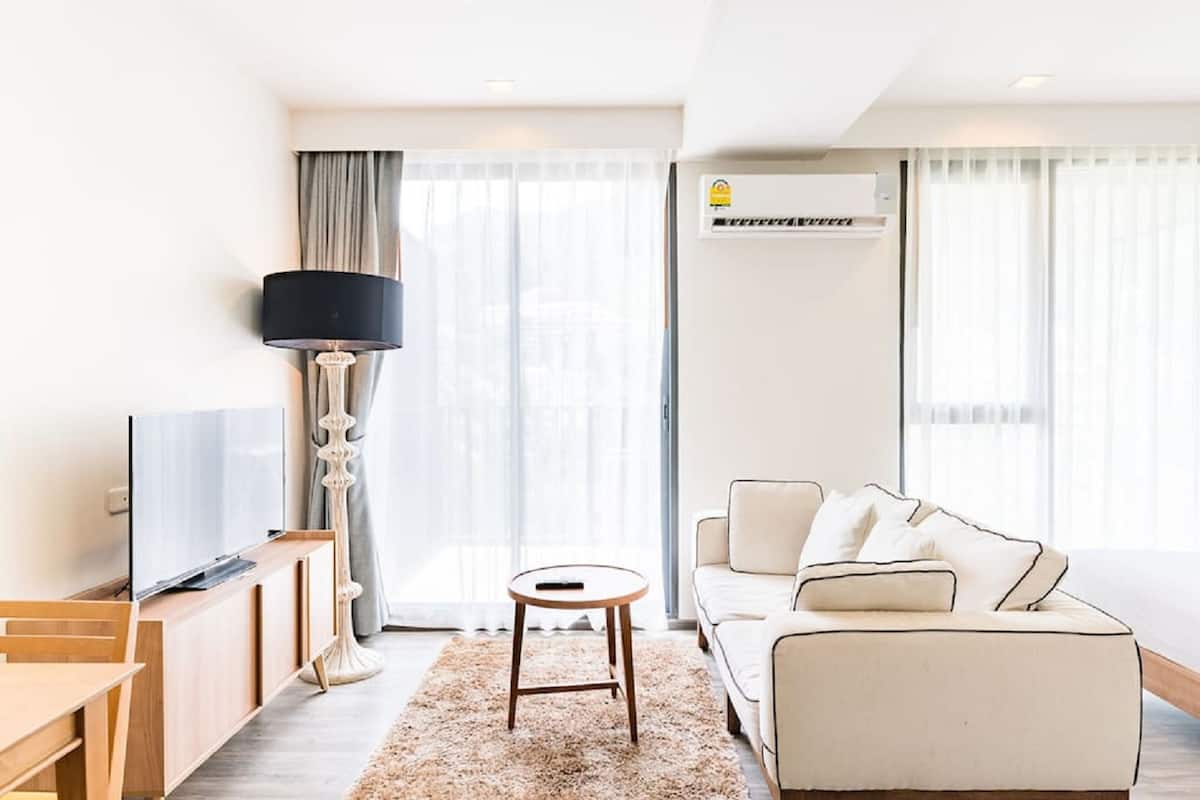 Una sala de estar moderna con un sofá, un televisor, una lámpara y una mesita.