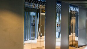 Un área de ascensor moderna con puertas de vidrio y barandillas de metal.