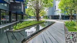 Un edificio moderno con fuente reflectante y vegetación.