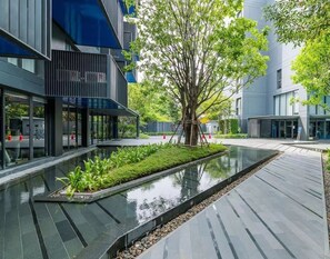 A modern building with a reflective water feature and greenery. - The Deck Patong (Patong)