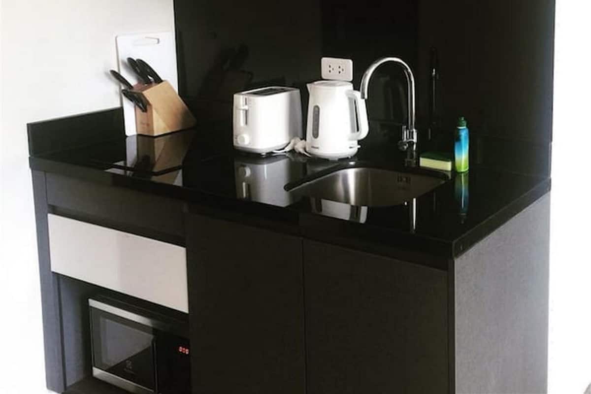 Una cocina compacta con cubierta negra, un tostador, una tetera y un lavamanos.