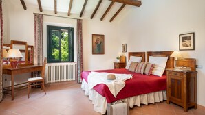 Un dormitorio con una cama de madera, un escritorio con lámpara, un radiador y una ventana con cortinas.