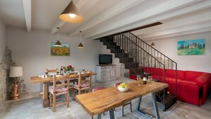Un comedor con una mesa y sillas de madera, un sofá rojo y una escalera.