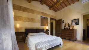 Ein Schlafzimmer mit einem großen Bett, einem Holzkleiderschrank und einem Spiegel.