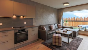 A modern kitchen with built-in appliances and a dining area with a sofa and ottoman.
