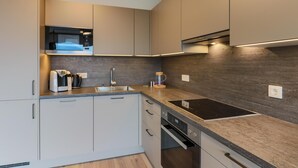 A modern kitchen with a built-in microwave, stainless steel sink, and a black induction cooktop.