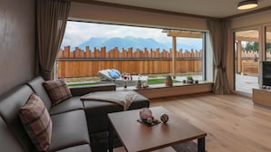 A modern living room with a sofa, a coffee table, and a large window offering a mountain view.