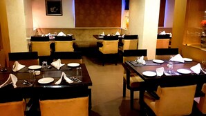 Un restaurant amb diverses taules preparades per dinar, cadascuna amb plats, coberts i serretes.