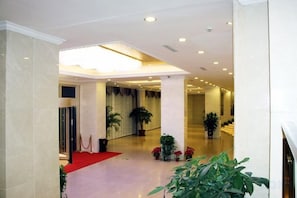A hotel lobby with a red carpet, potted plants, and a staircase leading to another area. - Shenhang Yinju Mingzhu Hotel (Jiashan)
