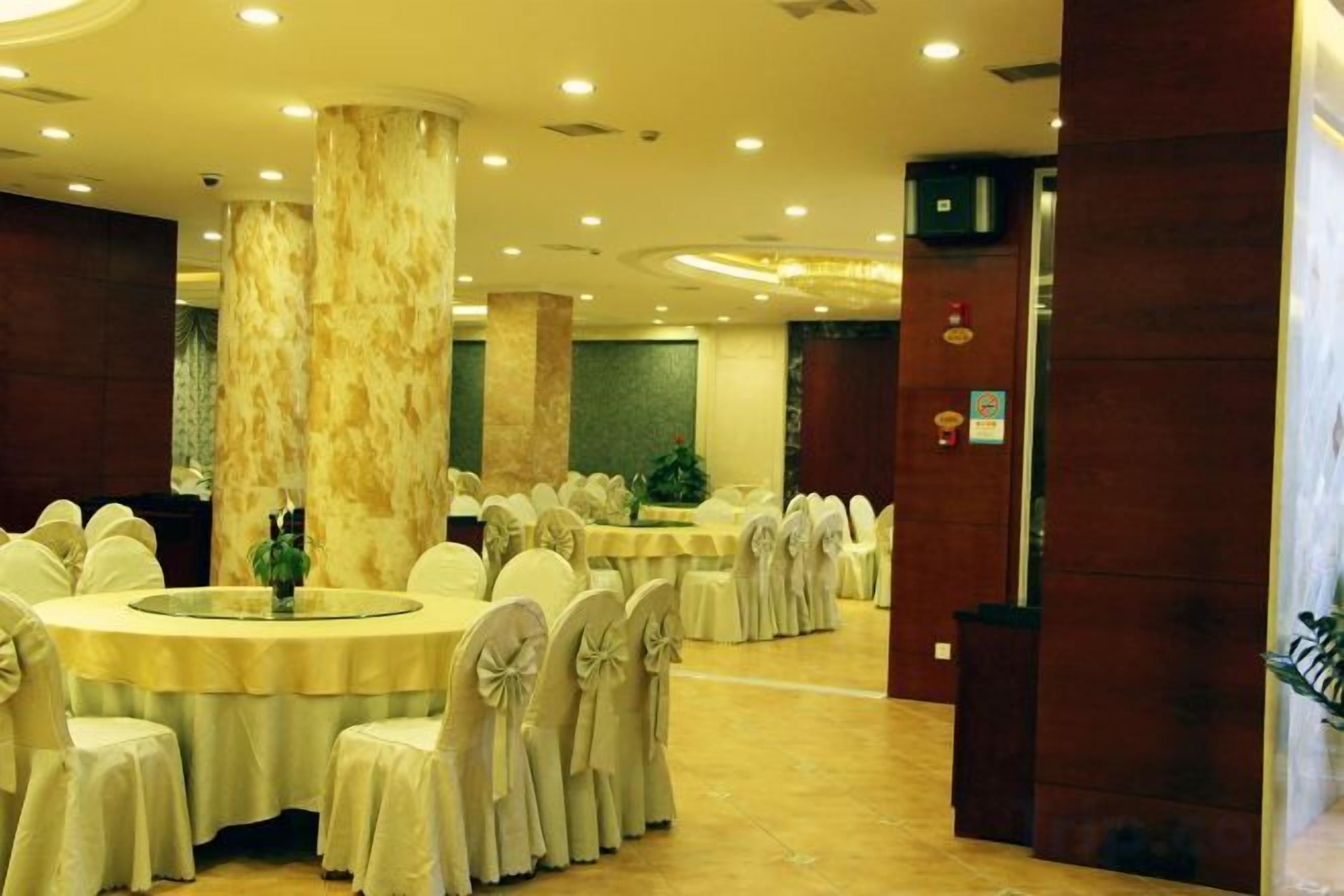 A banquet hall with round tables, chairs, and a marble pillar.