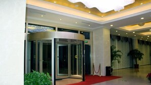 A lobby with a revolving door, a red carpet, and potted plants. - Shenhang Yinju Mingzhu Hotel (Jiashan)
