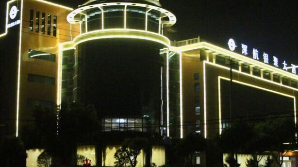 A modern building with a prominent circular tower and illuminated signage. - Shenhang Yinju Mingzhu Hotel (Jiashan)