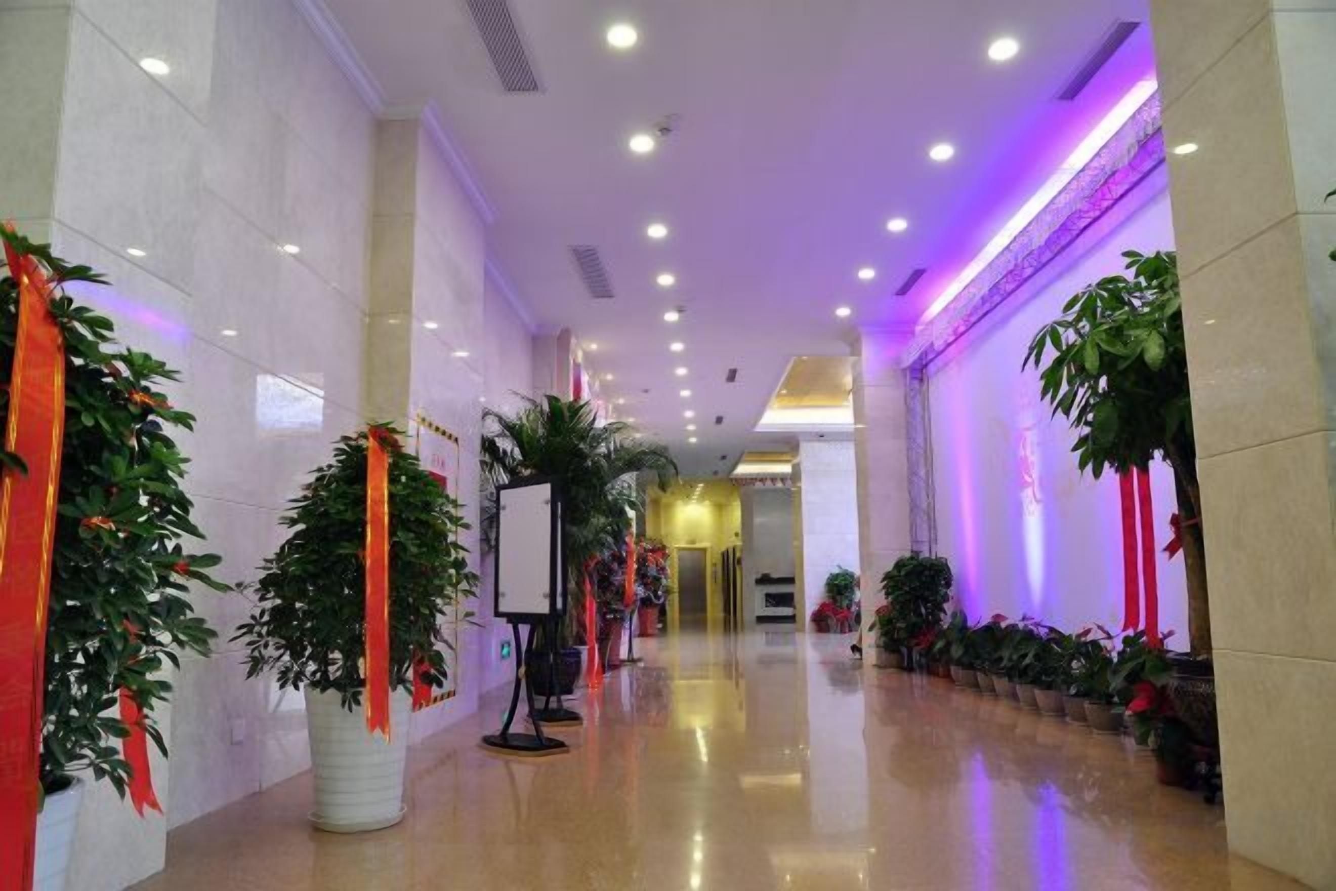 A hallway with potted plants, a whiteboard, and a reception desk.